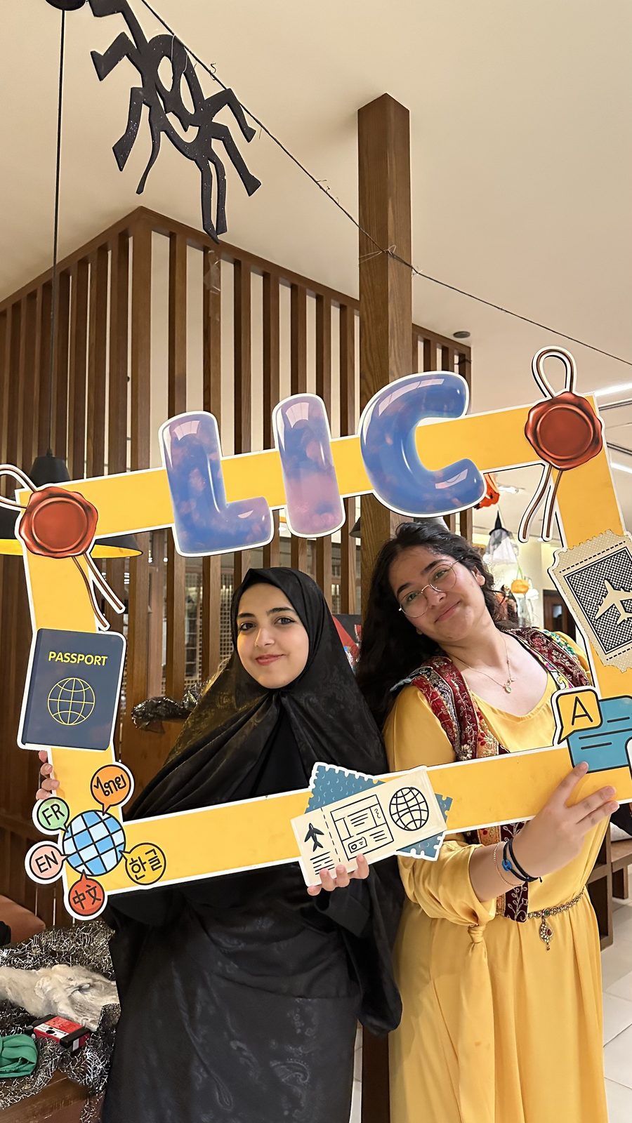 Two LIC members posing with the club's LIC photo-frame prop at an intercultural night