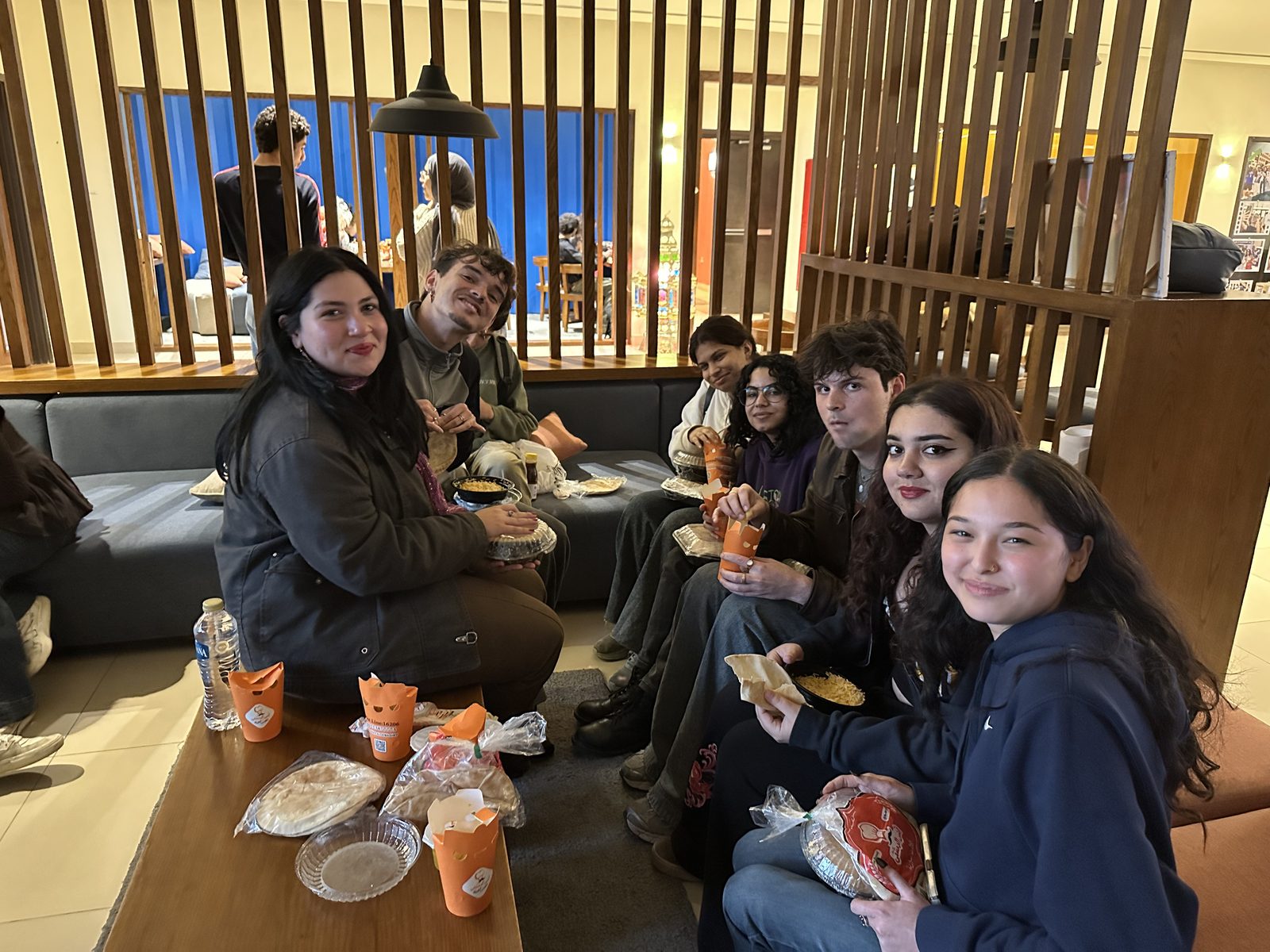 LIC students sharing food and conversation around a low table at a Language Café gathering